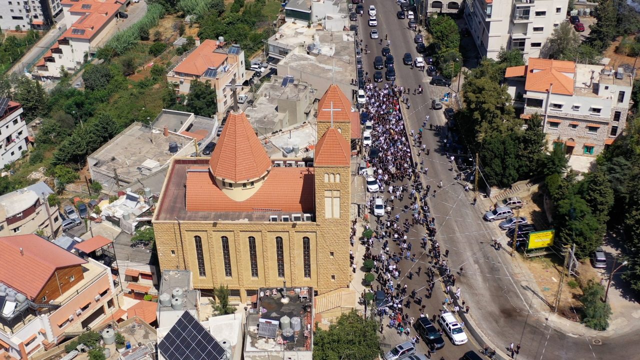 An aerial view shows mourners gathering outside the Saint Anthony church in the town of Kahale, east of Beirut, on August 11, 2023 during the funeral of Fadi Bejjani, a Christian Lebanese who succumbed to wounds inflicted during clashes that erupted two days earlier between residents of the town and members of the Lebanese Hezbollah group. The deadly violence broke out after a truck overturned on a road cutting through the town of Kahale, which residents claim was carrying weapons for the powerful Shiite movement. (Photo by AFP)