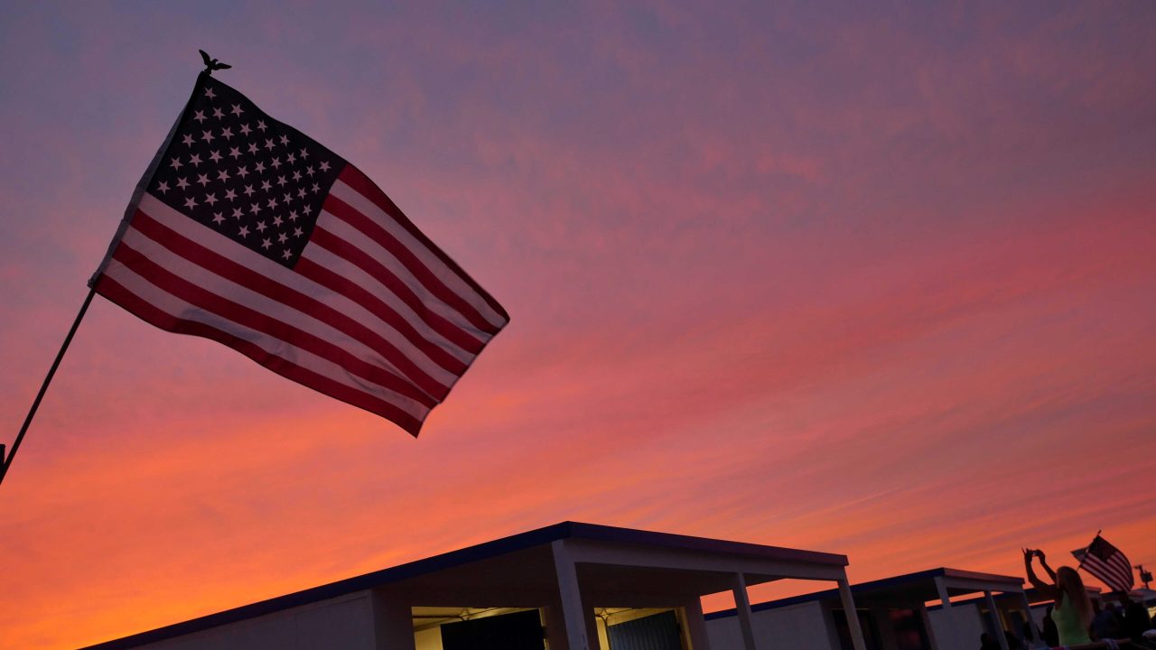 The American flag flies as a woman in silhouette takes a photograph during U.S. Independence Day celebrations in Atlantic Beach, New York July 3, 2016, ahead of the July 4th holiday. REUTERS/Shannon Stapleton