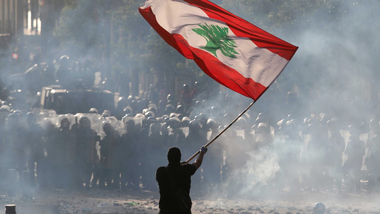FILE PHOTO: A demonstrator waves the Lebanese flag in front of riot police during a protest in Beirut FILE PHOTO: A demonstrator waves the Lebanese flag in front of riot police during a protest in Beirut, Lebanon, August 8, 2020. REUTERS/Goran Tomasevic/File Photo