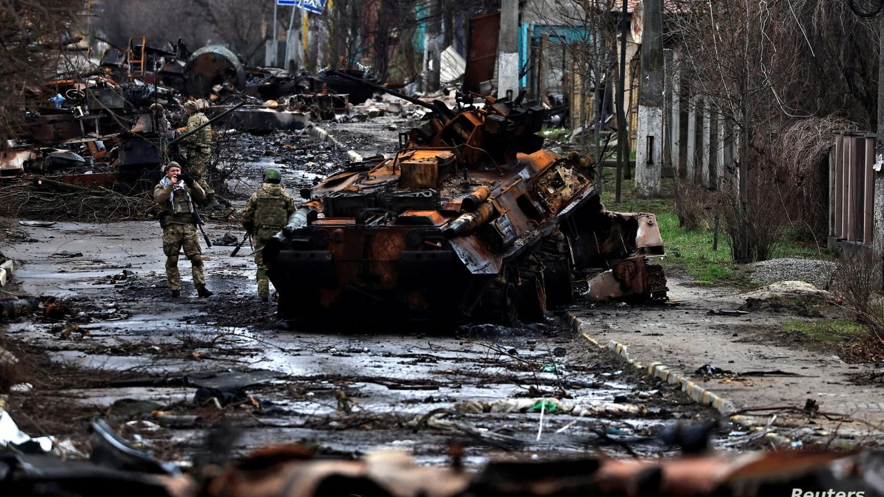 A soldier takes a photograph of his comrade as he poses beside a destroyed Russian tank and armoured vehicles, amid Russia's invasion on Ukraine in Bucha, in Kyiv region, Ukraine April 2, 2022. REUTERS/Zohra Bensemra     TPX IMAGES OF THE DAY