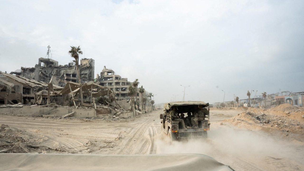 Israeli soldiers ride in a vehicle next to damaged buildings amid the ongoing ground operation of the Israeli army against the Palestinian Islamist group Hamas, in the Gaza Strip, in this handout image released November 18, 2023. Israel Defense Forces/Handout via REUTERS THIS IMAGE HAS BEEN SUPPLIED BY A THIRD PARTY