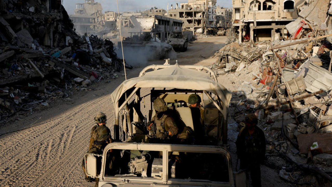 Israeli soldiers look on from a military vehicle as damaged buildings are seen in the background, amid the ongoing ground operation of the Israeli army against Palestinian Islamist group Hamas, in the Gaza Strip, September 13, 2024. REUTERS/Amir Cohen EDITOR'S NOTE: REUTERS PHOTOGRAPHS WERE REVIEWED BY THE IDF AS PART OF THE CONDITIONS OF THE EMBED. NO PHOTOS WERE REMOVED.