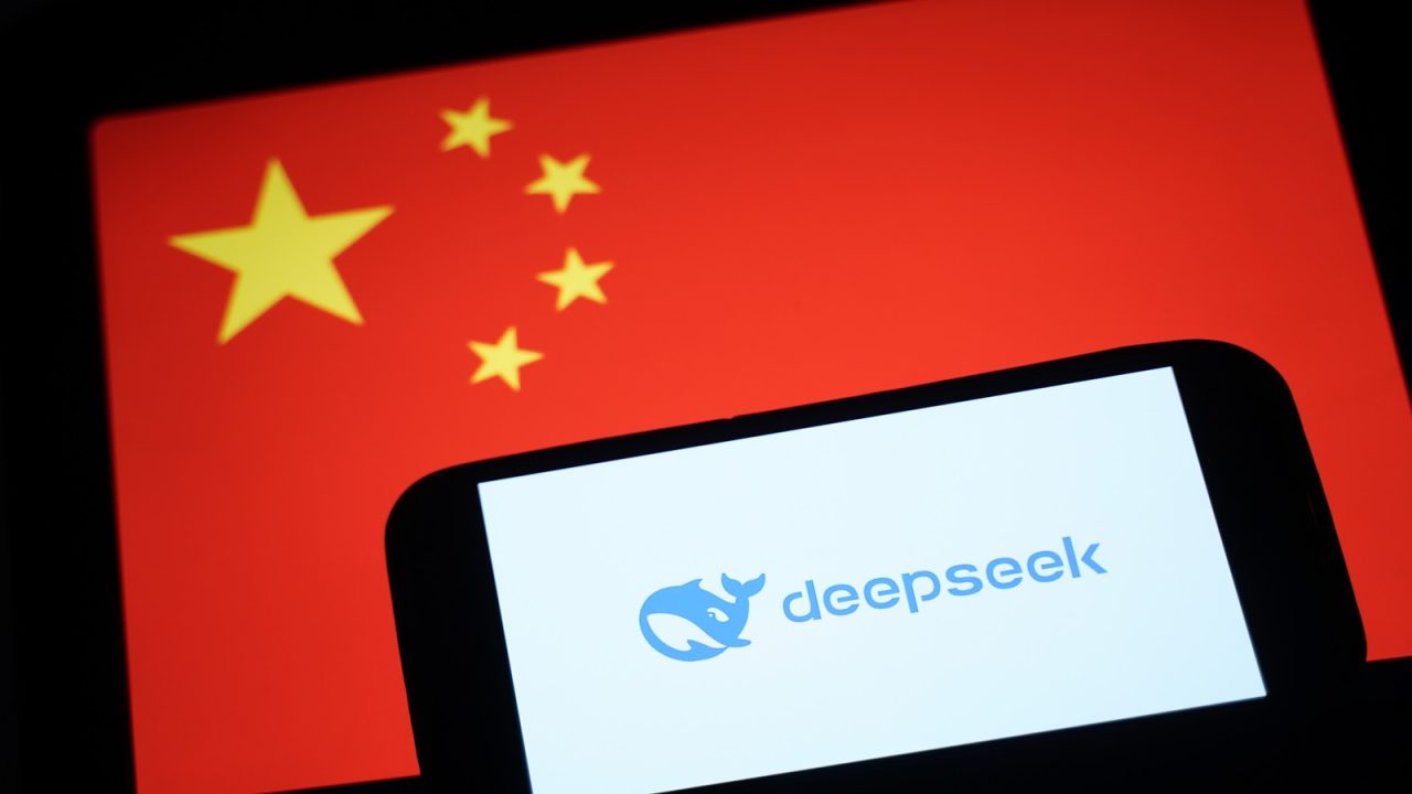 Illustrations Of DeepSeek As The Chinese AI App Causes NASDAQ Rout HONG KONG, CHINA - JANUARY 28: In this photo illustration, the DeepSeek logo is seen on a phone in front of a flag of China on January 28, 2025 in Hong Kong, China. Global tech stocks have plummeted following the emergence of DeepSeek, a Chinese AI startup that has developed a competitive AI model at a fraction of the cost of its US rivals, sparking concerns about the high valuations of tech giants like Nvidia. This development has led to significant declines in tech shares across Asia and Europe, with markets in both regions experiencing notable losses as investors reassess the AI landscape and its potential impact on the industry's future. (Photo illustration by Anthony Kwan/Getty Images)
