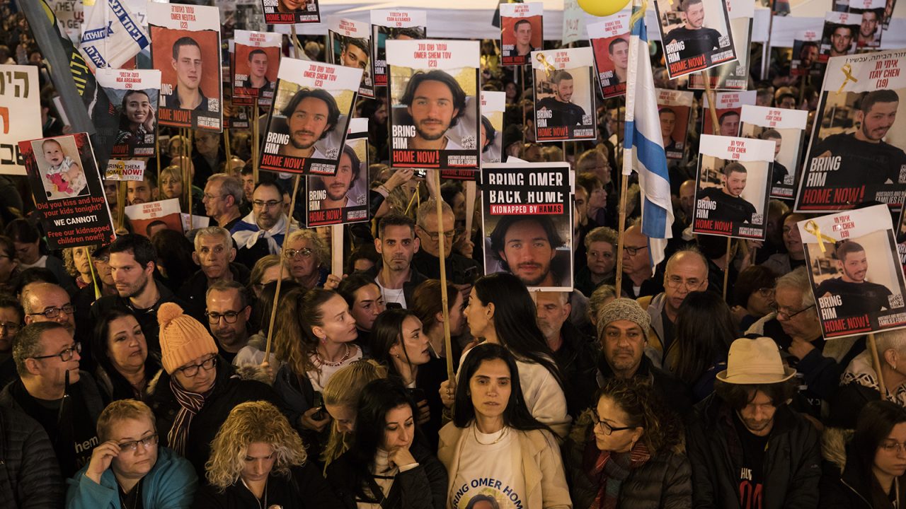 TEL AVIV, ISRAEL - JANUARY 13:  People hold photos of hostages  during a rally to mark 100 days of captivity for hostages by Hamas in Gaza on January 13, 2024 in Tel Aviv, Israel. The protest featured a 30-meter-long tunnel meant to simulate the conditions in which Israeli hostages are allegedly held in Gaza. More than 100 Israeli hostages captured on Oct. 7 remain held in Gaza by Hamas and other militant groups, according to Israeli authorities.  (Photo by Amir Levy/Getty Images)