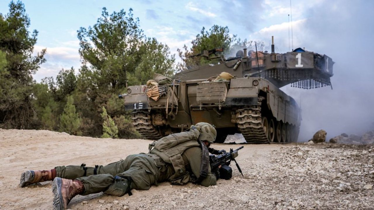 An Israeli army soldier lies prone with a rifle near a battle tank at a position in the upper Galilee region of northern Israel near the border with Lebanon on November 1, 2023 amid increasing cross-border tensions between Hezbollah and Israel as fighting continues in the south with Hamas militants in the Gaza Strip. (Photo by Jalaa MAREY / AFP) (Photo by JALAA MAREY/AFP via Getty Images)