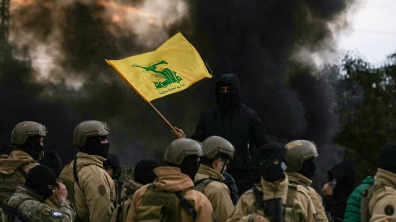 A Hezbollah supporter waves the group's flag in front of Lebanese army troops, as protesters burn tyres to block the road leading to Beiruts international airport, following the visit of US Deputy Special Envoy for the Middle East Morgan Ortagus, during which she met with the country's president, on February 7, 2025. Ortagus on February 7 warned against any Hezbollah presence in Lebanon's new government, saying the Iran-backed group was "defeated" in its war with Israel. (Photo by Ibrahim AMRO / AFP)