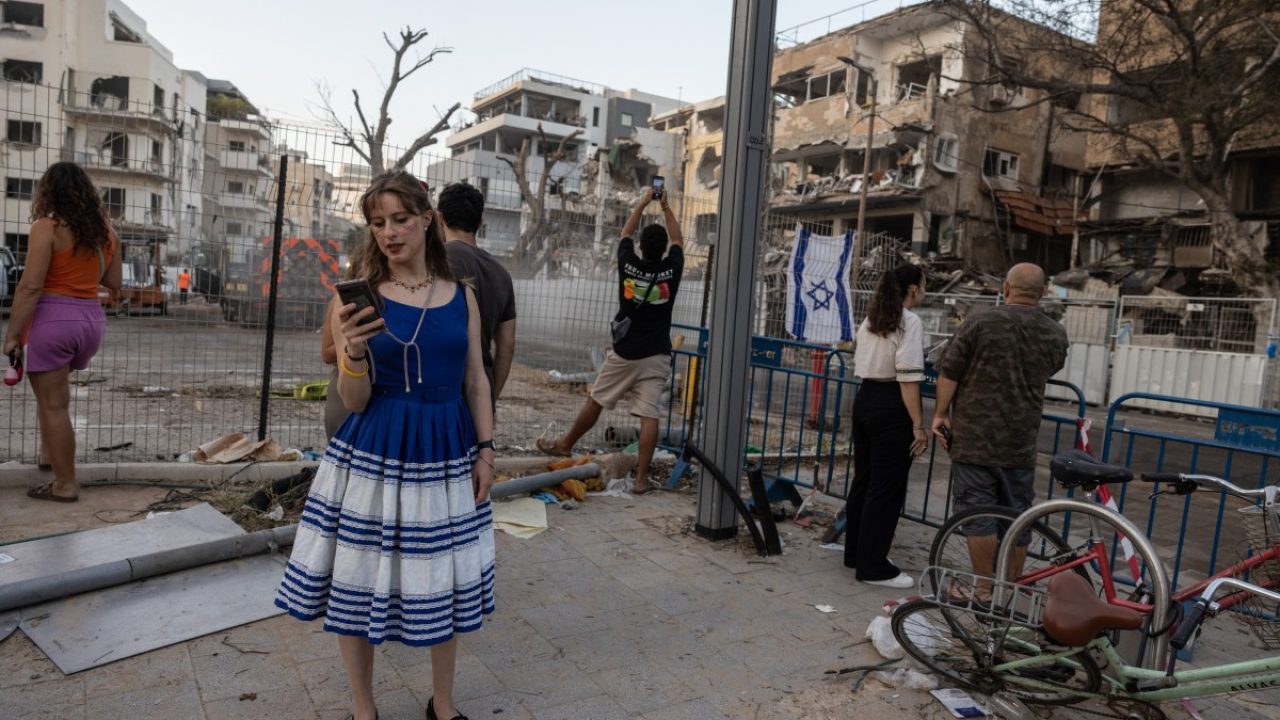 People visit the site of an Iranian missile attack in central Tel Aviv which left several destroyed buildings, on June 16, 2025. Israel and Iran traded heavy fire for a fourth straight day on June 16, with mounting casualties and expanding targets marking a sharp escalation in hostilities between the longtime foes. (Photo by Menahem Kahana / AFP)