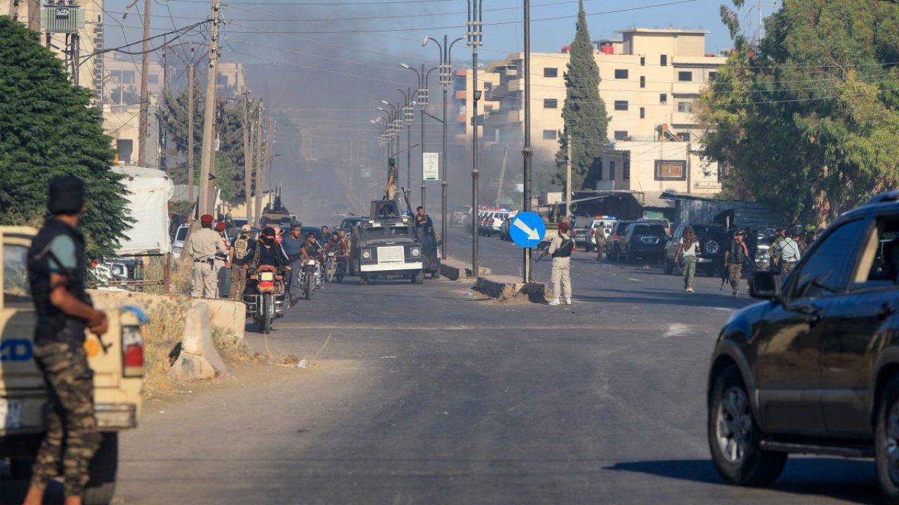 Members of Syria's security forces look on as smoke billows during clashes between Bedouin tribes and Druze fighers in an area between Mazraa and Walga near the predominantly Druze city of Sweida on July 14, 2025. Israeli Defence Minister Israel Katz issued a warning to Damascus on July 14 after the military struck several tanks in southern Syria to prevent them from reaching a Druze village near the scene of sectarian clashes. (Photo by Bakr ALKASEM / AFP)