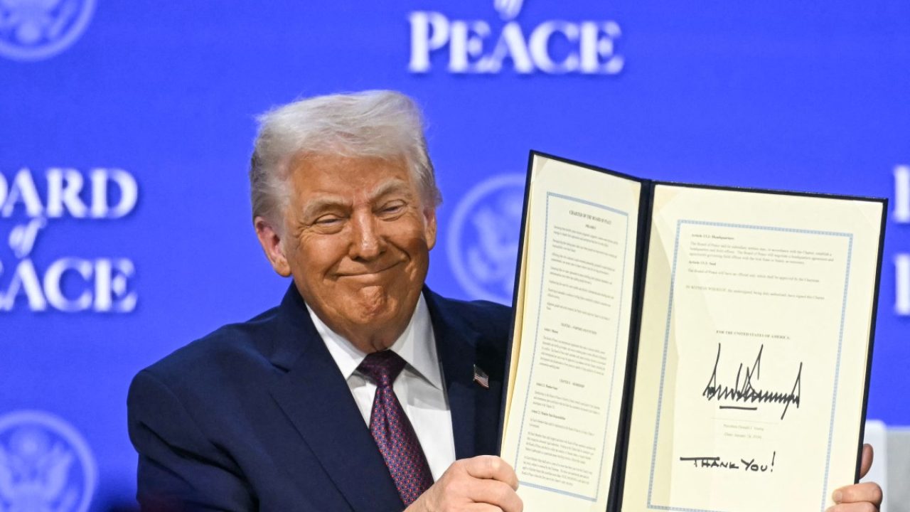 US President Donald Trump holds a signed founding charter at the "Board of Peace" meeting during the World Economic Forum (WEF) annual meeting in Davos on January 22, 2026. US President Donald Trump will show off his new "Board of Peace" at Davos on January 22, 2026 burnishing his claim to be a peacemaker a day after backing off his own threats against Greenland. Originally meant to oversee the rebuilding of Gaza after the war between Hamas and Israel, the board's charter does not limit its role to the Strip, and has sparked concerns that Trump wants it to rival the United Nations. (Photo by Fabrice COFFRINI / AFP)