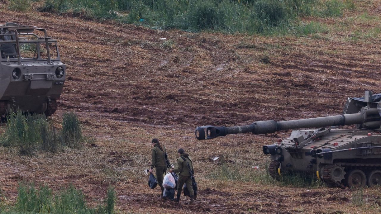 Israeli army soldiers walk next to a self-propelled Howitzer artillery gun positioned in the upper Galilee in northern Israel near the border with southern Lebanon on March 29, 2026. Lebanon was drawn into the Middle East war on March 2, when pro-Iran Hezbollah launched rockets towards Israel in response to US-Israeli strikes that killed Iranian supreme leader on February 28. (Photo by Jalaa MAREY / AFP) /