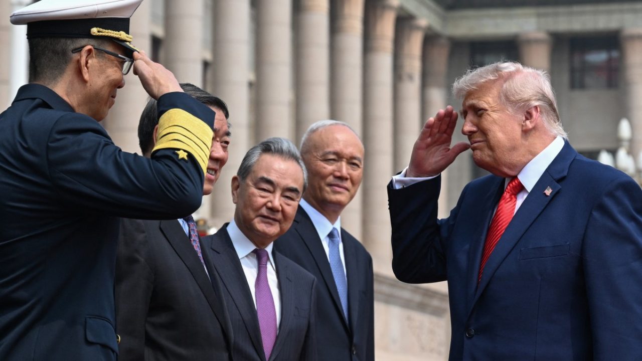 US President Donald Trump (R) salutes China's Defence Minister Dong Jun (L) during a welcome ceremony at the Great Hall of the People in Beijing on May 14, 2026. (Photo by Kenny HOLSTON / POOL / AFP)