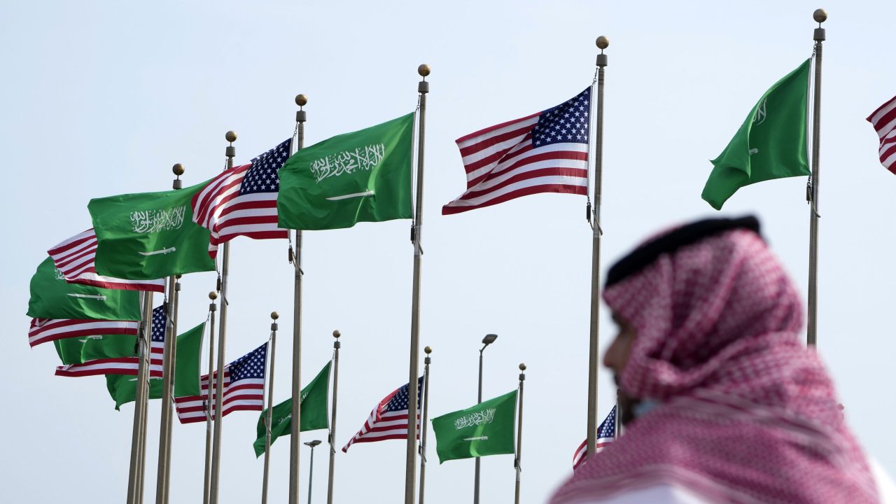 A man stands under American and Saudi Arabian flags prior to a visit by U. S. President Joe Biden, at a square in Jeddah, Saudi Arabia, Thursday, July 14, 2022. (AP Photo/Amr Nabil)