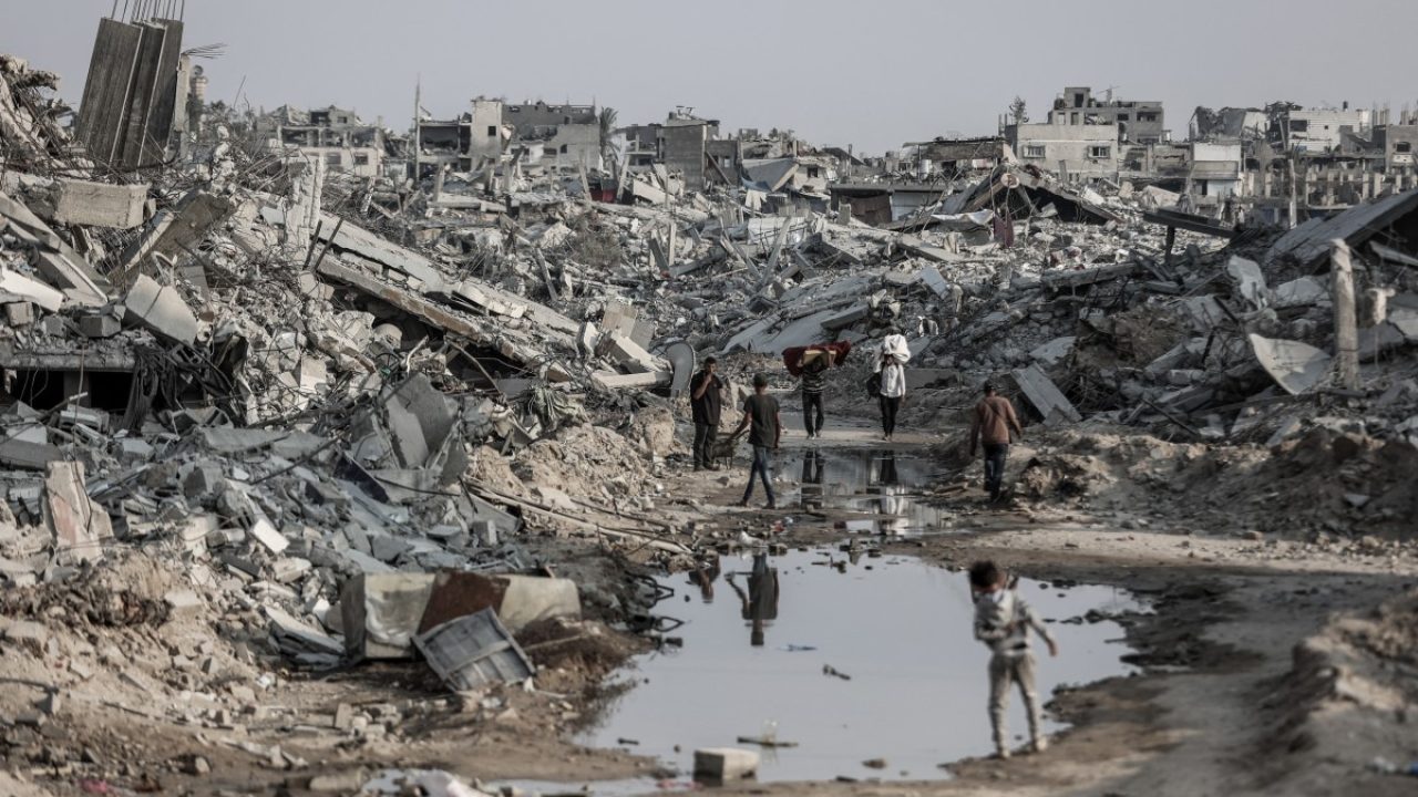 Palestinians make their way through the rubble of destroyed buildings in Jabalia, in the northern Gaza Strip, on November 7, 2025. The United Nations said on November 4 it had distributed food parcels to one million people in Gaza since the ceasefire, but warned it was still in a race to save lives. The UN's World Food Programme stressed all crossing points into the Gaza Strip should be opened to flood the famine-hit Palestinian territory with aid, adding that no reason was given why the northern crossings with Israel remained closed. (Photo by Omar AL-QATTAA / AFP)