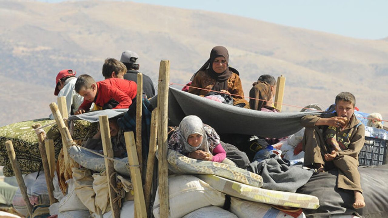 Syrian refugees, fleeing the recent fighting in Arsal, wait with their belongings in Majdel Anjar in the Bekaa valley, near the Lebanese border with Syria August 8, 2014. The refugees, who had sought shelter in Arsal, were attempting to head back to Syria; however, they say Syrian authorities at the border rejected them until further investigation to verify their identities and statuses. REUTERS/Hassan Abdallah (LEBANON - Tags: POLITICS CIVIL UNREST) - RTR41Q6X