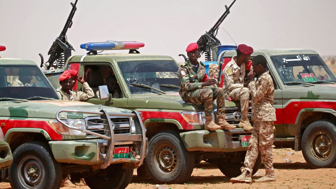 Members of Sudanese paramilitary Rapid Support Forces (RSF) celebrate as they lead dozens of African nationals, caught as they tried to cross into Libya illegally, in front of the media a desert area called Gouz Abudloaa, about 100 kilometres north of Khartoum, on September 25, 2019. - Sudanese paramilitaries said they have captured 138 Africans, including dozens of Sudanese, trying to enter neighbouring Libya illegally. (Photo by ASHRAF SHAZLY / AFP)        (Photo credit should read ASHRAF SHAZLY/AFP via Getty Images)