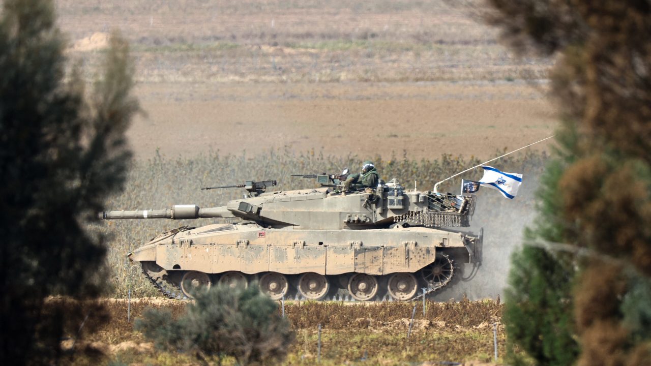 A picture taken in southern Israel near the border with the Gaza Strip on December 8, 2023, shows an Israeli army tank rolling in a field, amid continuing battles between Israel and the militant group Hamas. (Photo by JACK GUEZ / AFP)