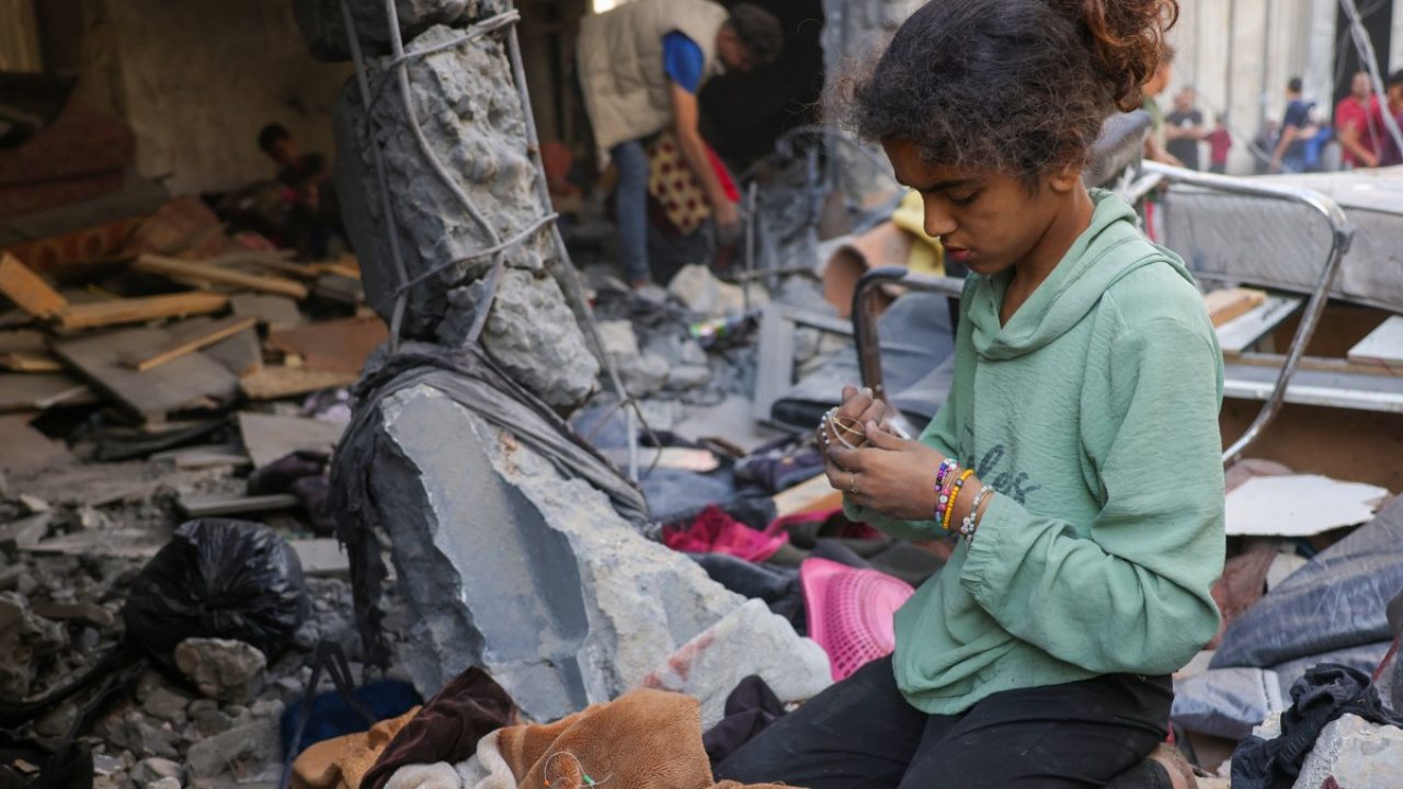A girl collects belongings as Palestinians check the site of an overnight Israeli strike, in Jabalia in the central Gaza Strip, on May 30, 2025, amid the war between Israel and the Palestinian Hamas militant movement. Israel's far-right National Security Minister Itamar Ben Gvir said on May 30 it was time to use "full force" in Gaza, after Hamas said a new US-backed truce proposal failed to meet its demands. (Photo by Bashar TALEB / AFP)