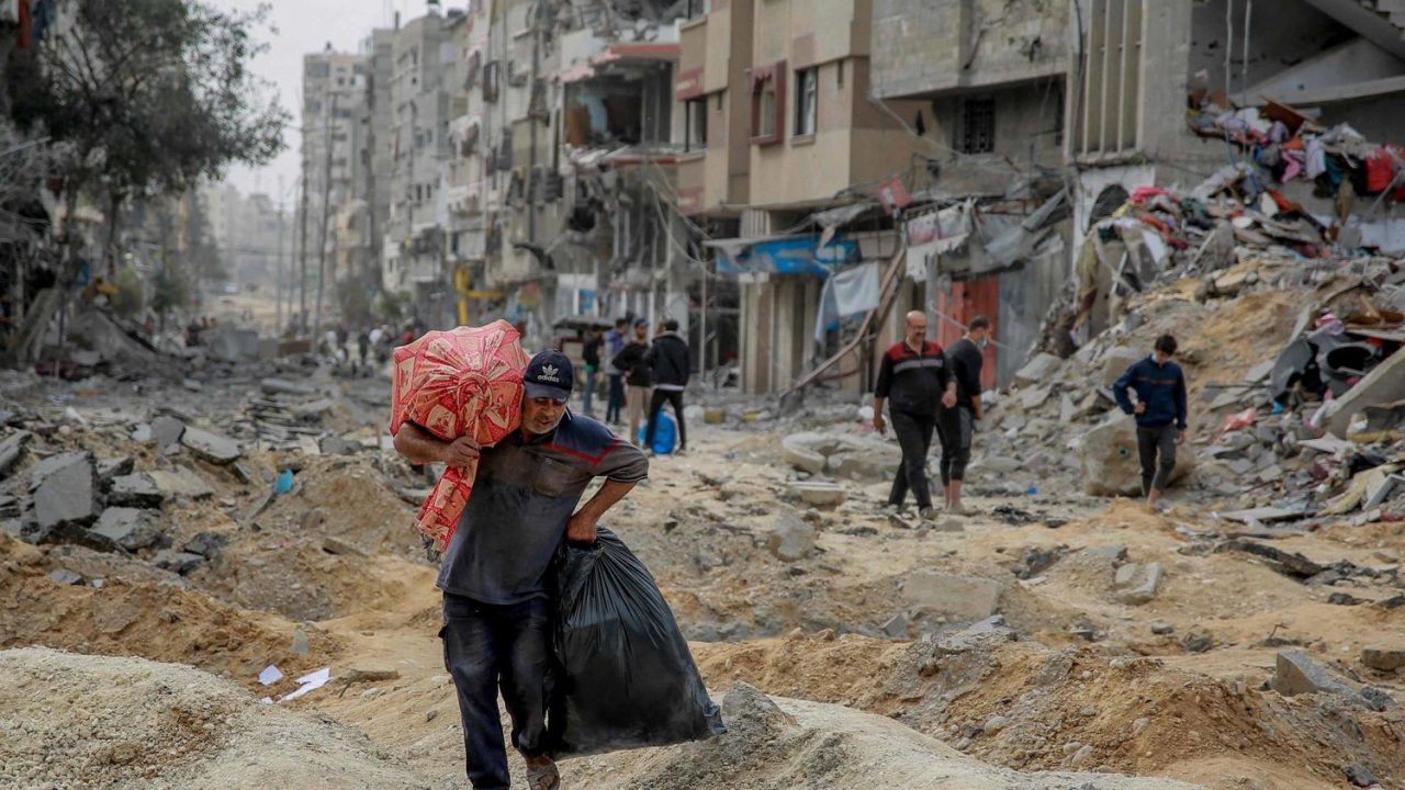 A man walks with a few personal items as Palestinians leave Gaza City to safer areas in the south on November 25, 2023, on the second day of a truce between Israel and Hamas. Hamas is expected to release another 14 Israeli hostages in exchange for 42 Palestinian prisoners on Saturday, the second day of a four-day truce in their seven-week war. (Photo by Omar El-Qattaa / AFP)