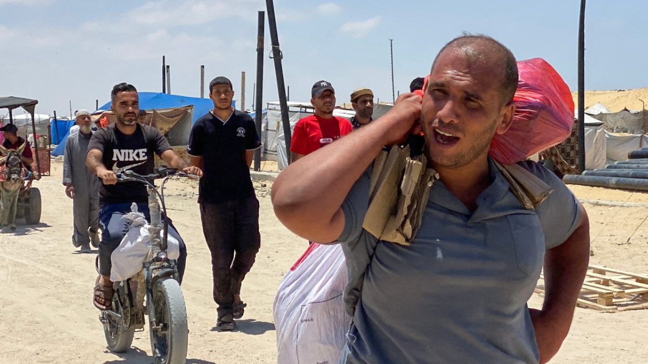 Displaced Palestinians carry parcels as they return from an aid distribution center in Khan Yunis in the southern Gaza Strip on May 28, 2025. The United Nations on May 28 condemned a US-backed aid system in Gaza following a chaotic food distribution where 47 people were injured, after Israel allowed supplies in at a trickle last week, easing a full blockade imposed on the besieged Palestinian territory for over two months. (Photo by AFP)