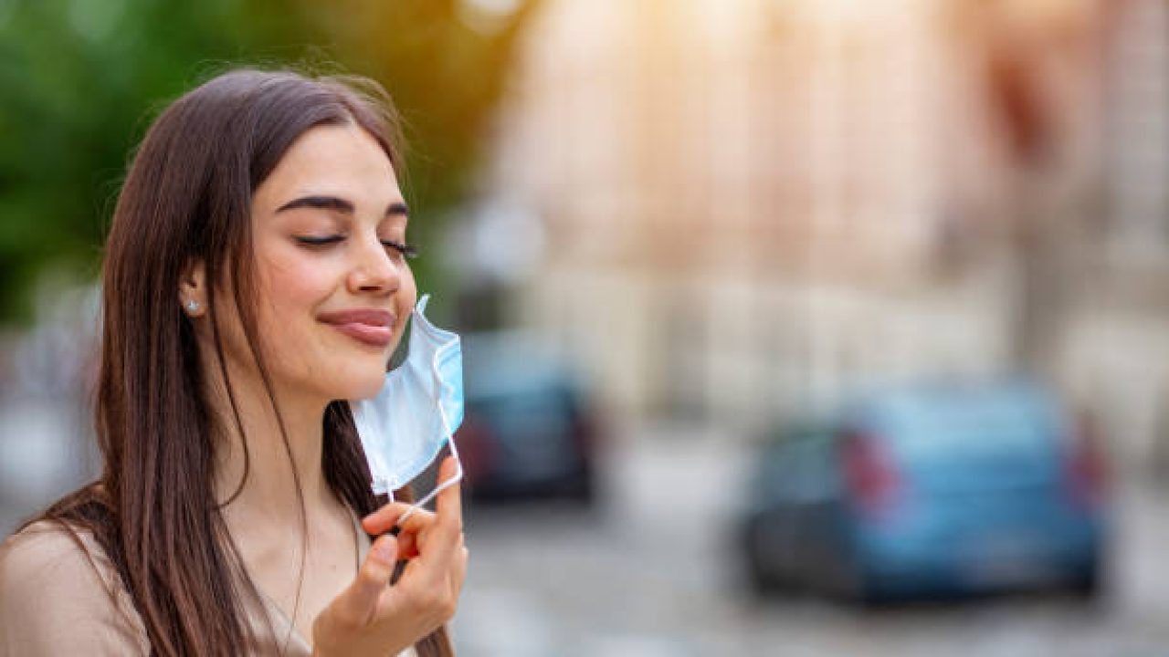 istockphoto-1224400698-612x612 Woman during pandemic isolation at city. Removing mask from face.. Woman holding mask. Quarantine is over concept. Woman taking off mask outdoor. End of pandemic coronavirus concept. NCoV, Covid 19.