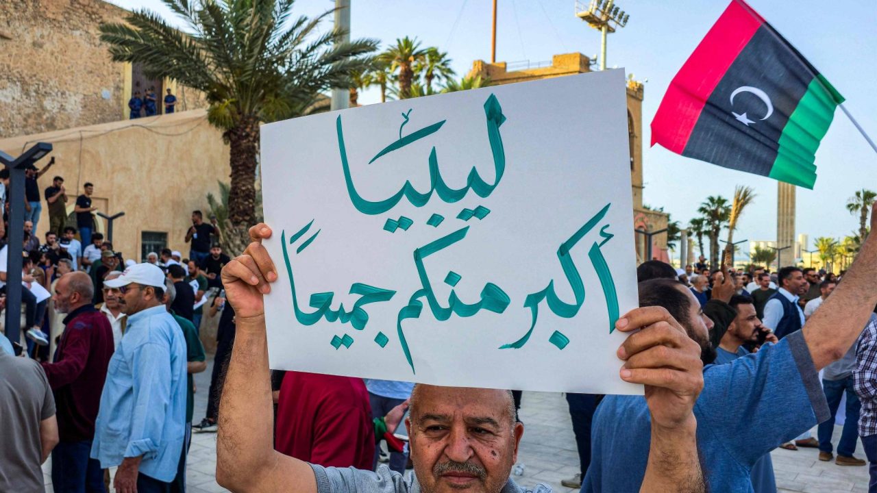 A man holds a sign reading in Arabic "Libya is greater than all of you", as demonstrators gather for an anti-government protest, calling upon the Government of National Unity (GNU) headed by Abdulhamid Dbeibah to resign, at the Martyrs' Square in Libya's capital Tripoli on May 23, 2025. (Photo by AFP)