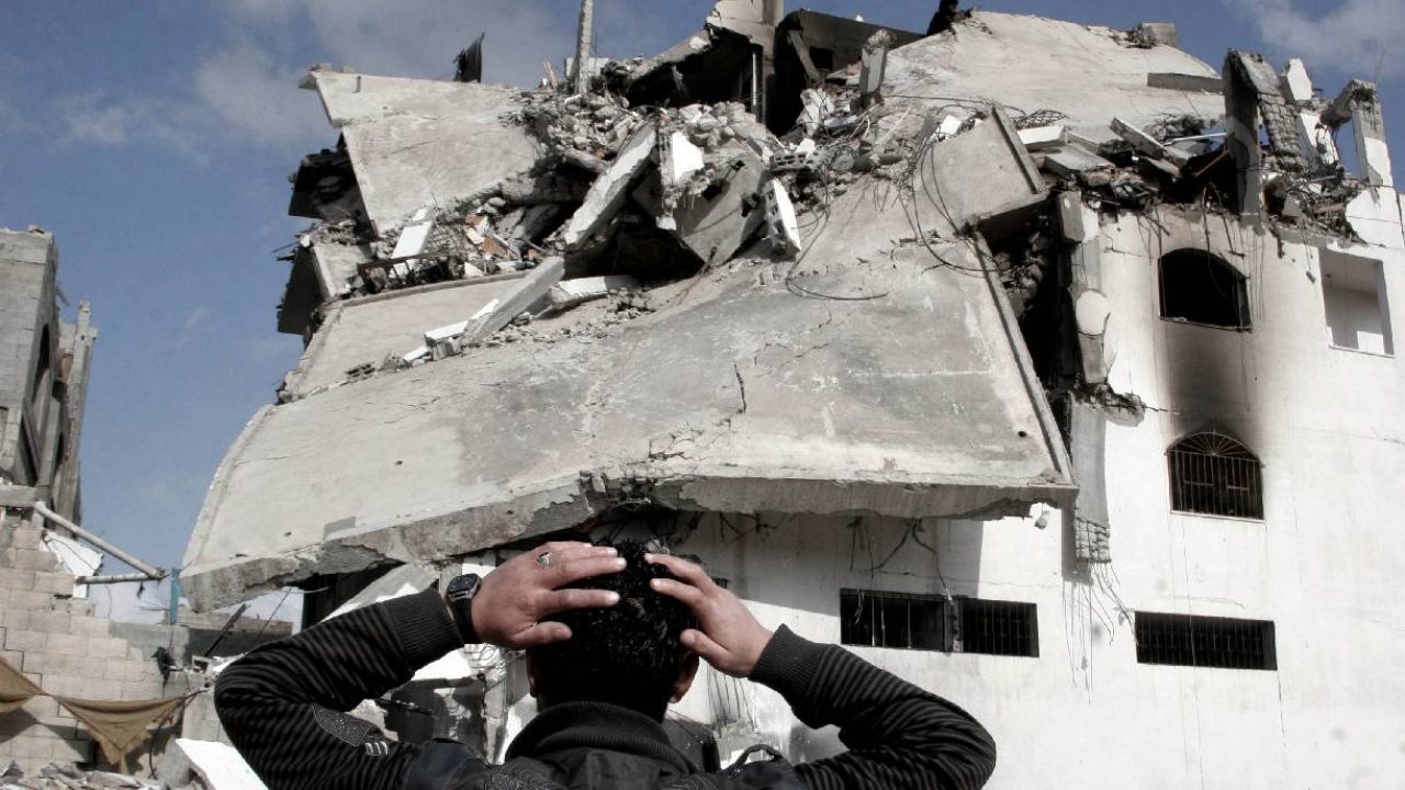 man looking at destroyed building in gaza