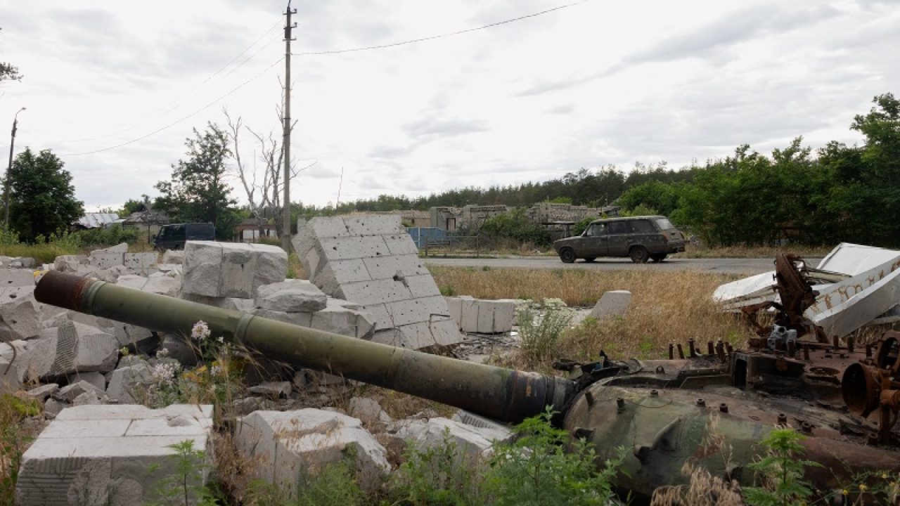 A car drives along the road past a partialy burnt tank in the city of Svyatohirs'k, Donetsk region on June 26, 2025, amid the Russian invasion of Ukraine. (Photo by Tetiana DZHAFAROVA / AFP)