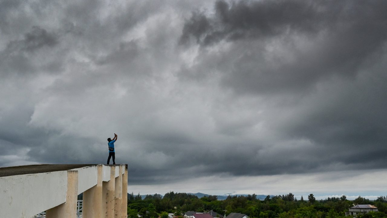 A man takes photos of dark clouds from a tsunami evacuation building on the eve of the 19th anniversary of the 2004 Indian Ocean earthquake and tsunami which killed over 200,000 people in 14 countries, with Aceh recording the highest death toll, in Banda Aceh on December 25, 2023. (Photo by CHAIDEER MAHYUDDIN / AFP)
